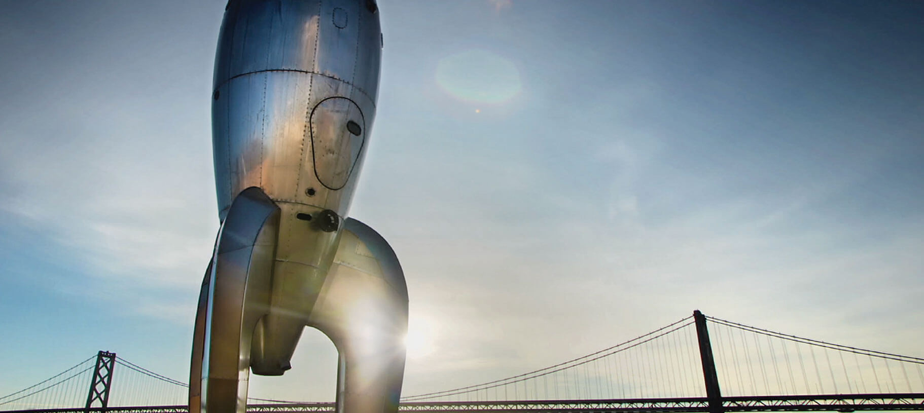 Large-scale retro-futuristic rocketship sculpture fabricated by Five Ton Crane and Engineered Artworks, installed at Pier 14 and Wings Over the Rockies Museum